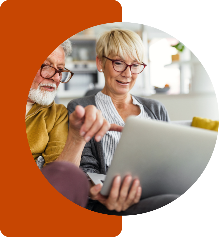A woman is using a laptop, while a man sitting next to her is pointing at the laptop.